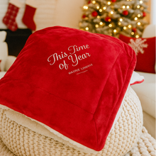 Load image into Gallery viewer, Red Velvet blanket with White Sheerling back. &#39;This Time of Year&#39; embraoidered text on a textured surface in a festive living room.
